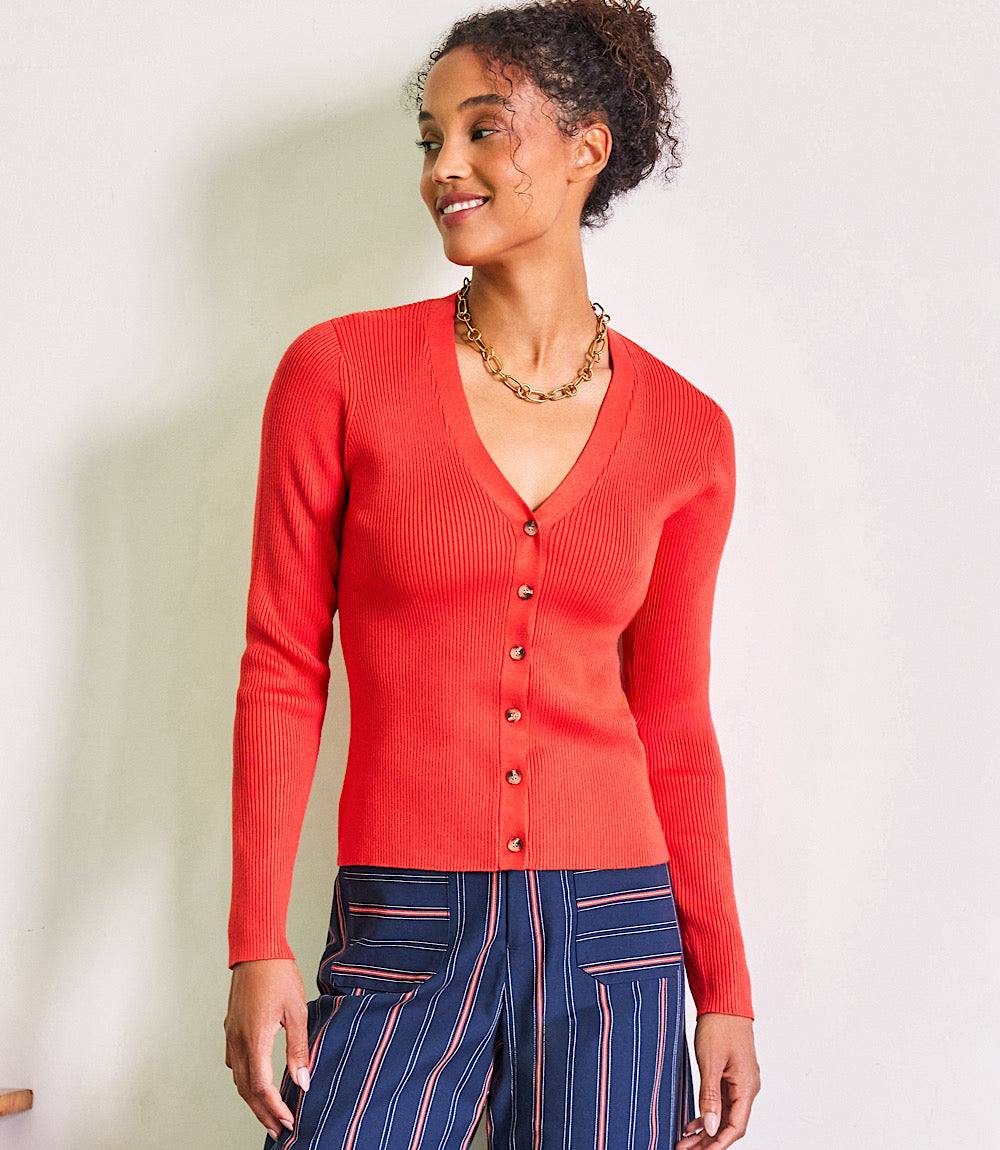 Woman wearing red ribbed cardigan sweater with button front closure and V-neckline