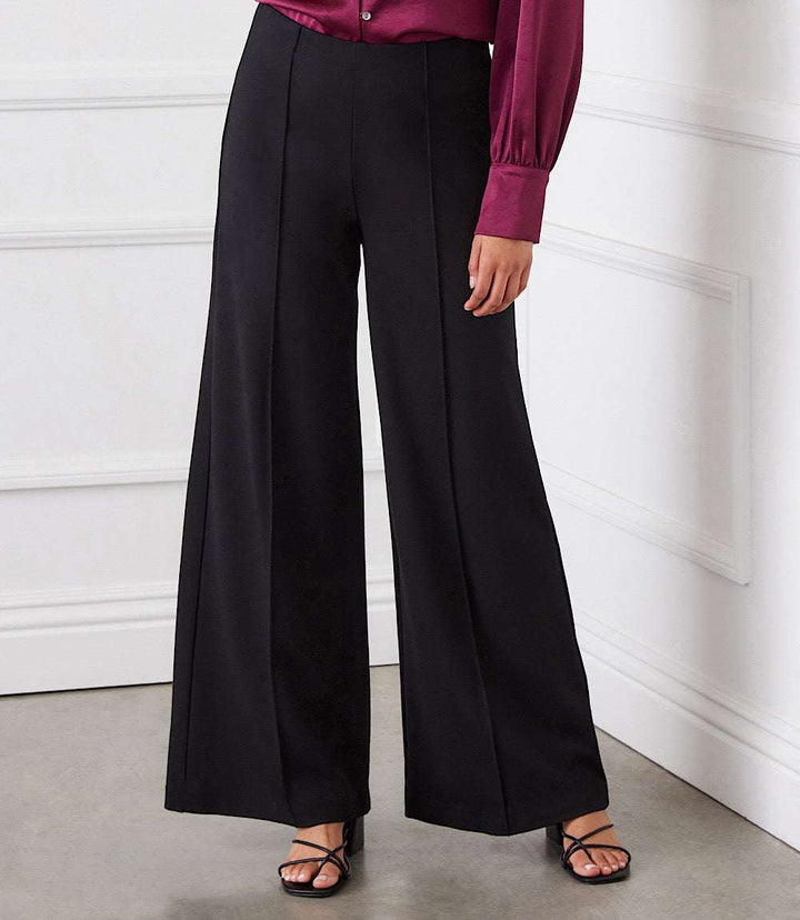 Black Luna Wide Leg Pants with pintuck detail and elasticized waist, paired with a purple blouse and black strappy heels.