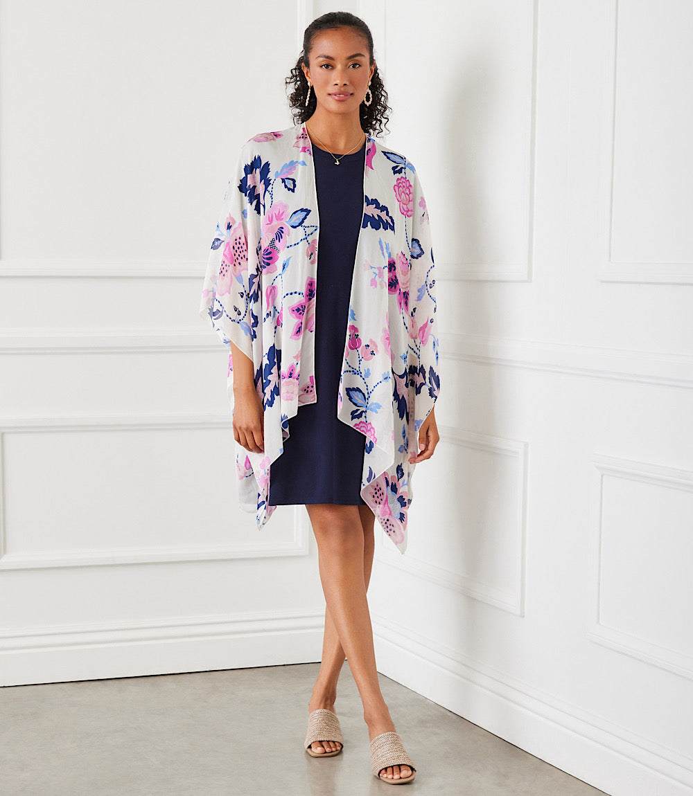 Woman wearing semi-sheer floral open front jacket with asymmetric hem over black dress