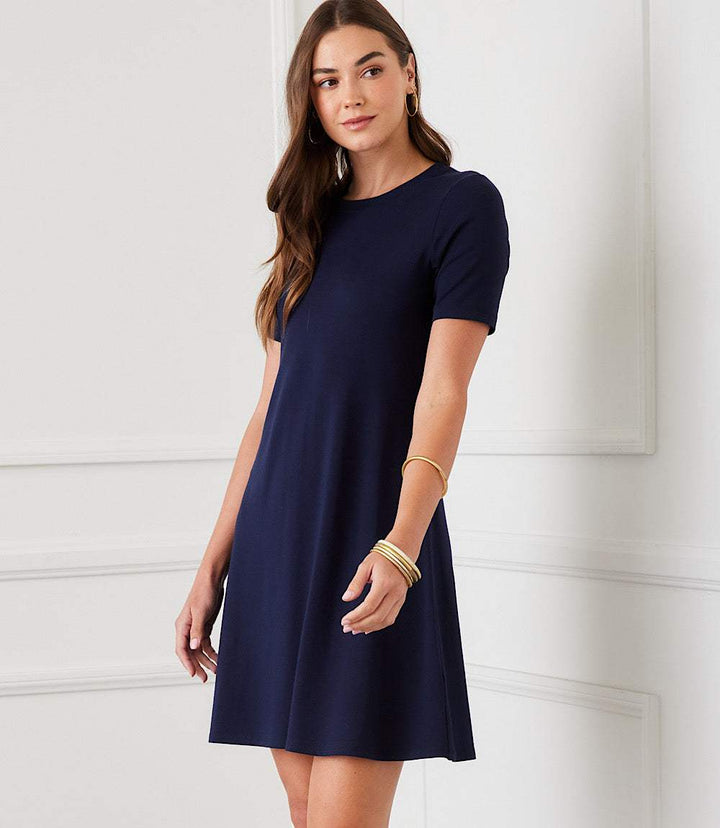 Woman wearing navy blue short sleeve A-line dress with crew neck and fitted waist, casual chic style
