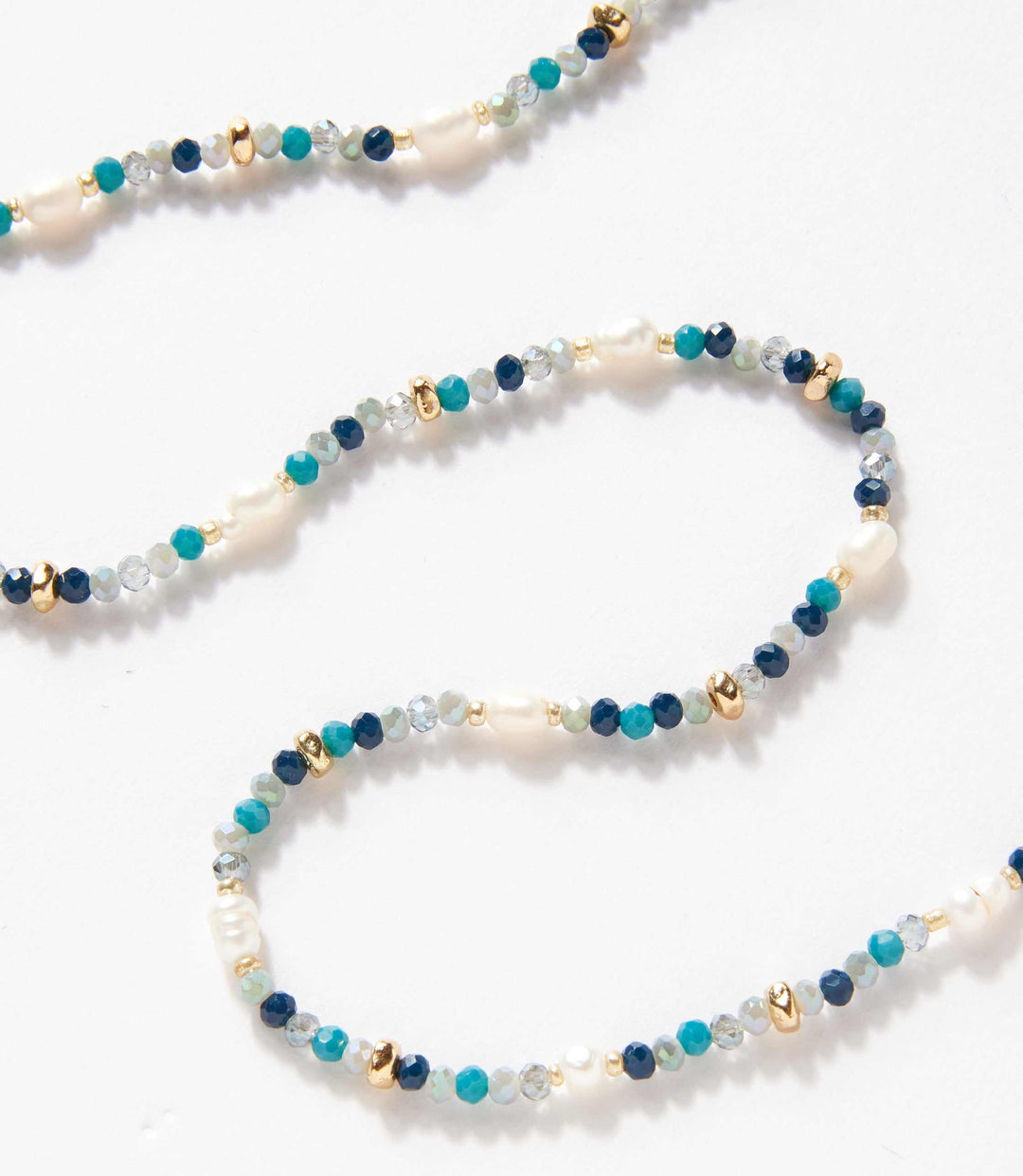 Beaded gemstone and pearl stretch bracelet with mixed gemstones and gold accents on white background