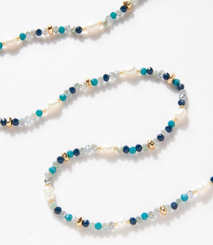 Beaded gemstone and pearl stretch bracelet with mixed gemstones and gold accents on white background