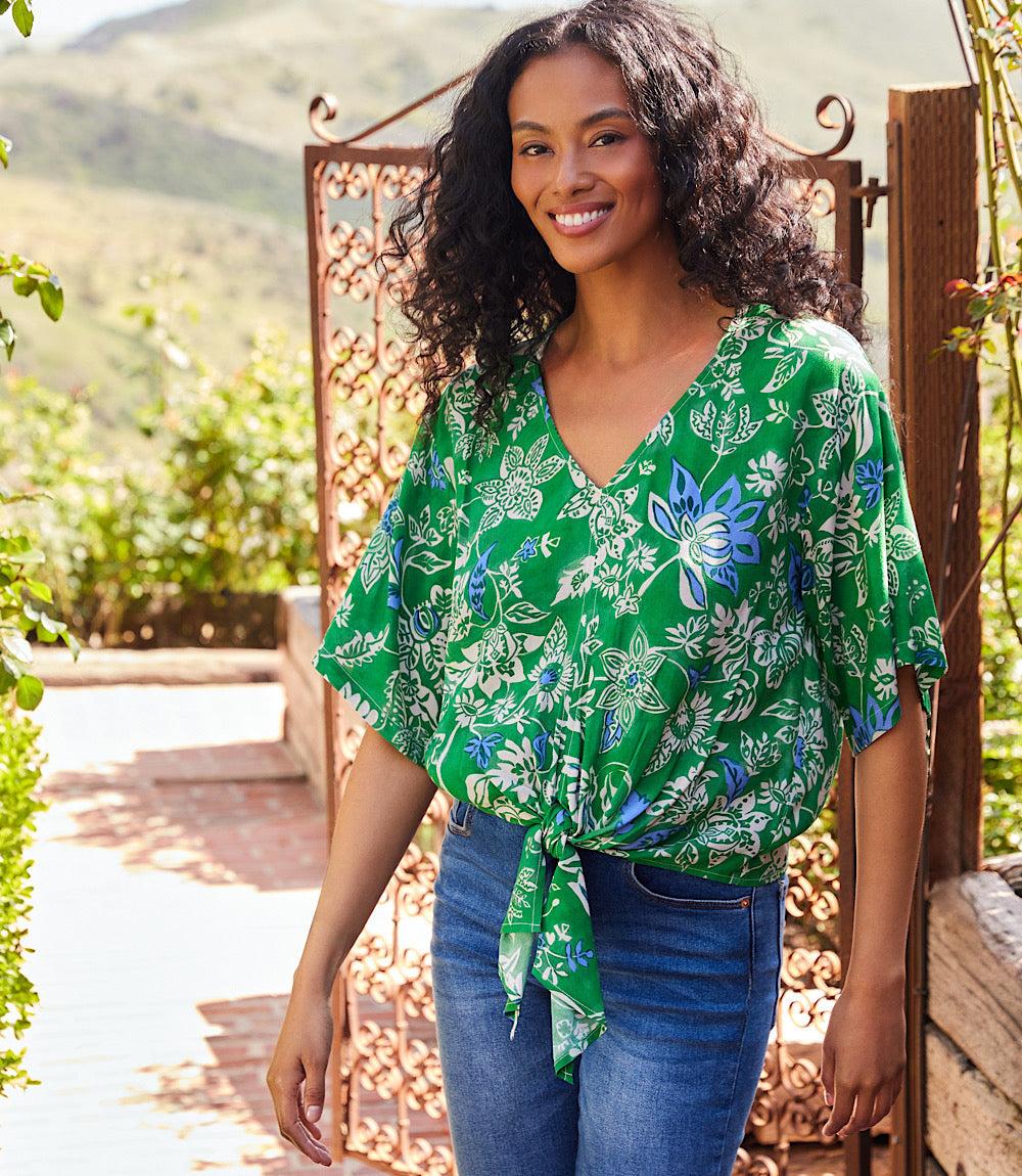 Woman wearing green short sleeve tie-front top with blue and cream floral print outdoors