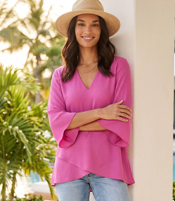 Woman wearing a silky crepe Bracelet Sleeve Asymmetric Top with flare sleeves and layered asymmetrical hem