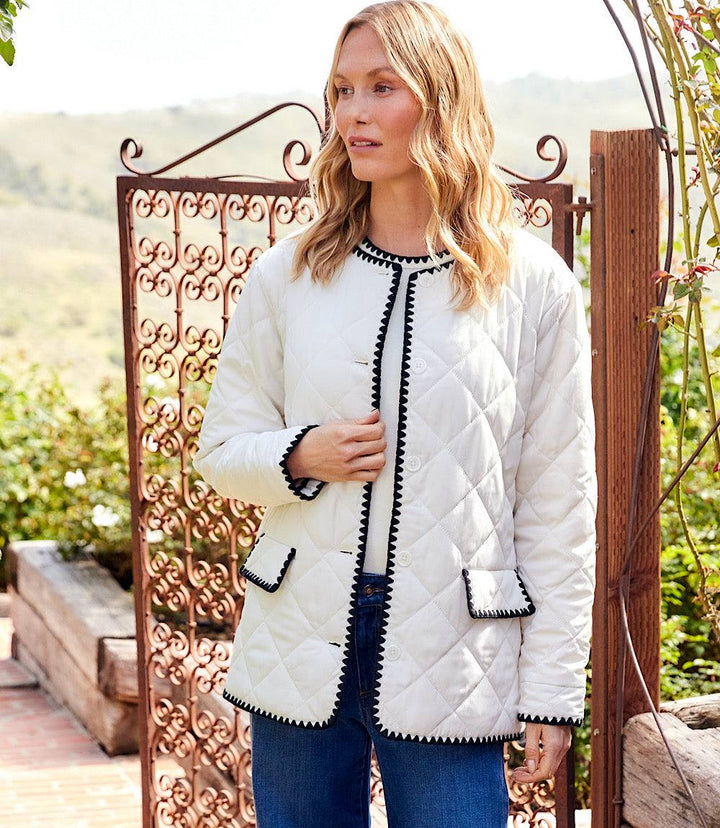 Woman wearing white Edge Stitch Quilted Jacket with black contrast trim and front flap pockets outdoors