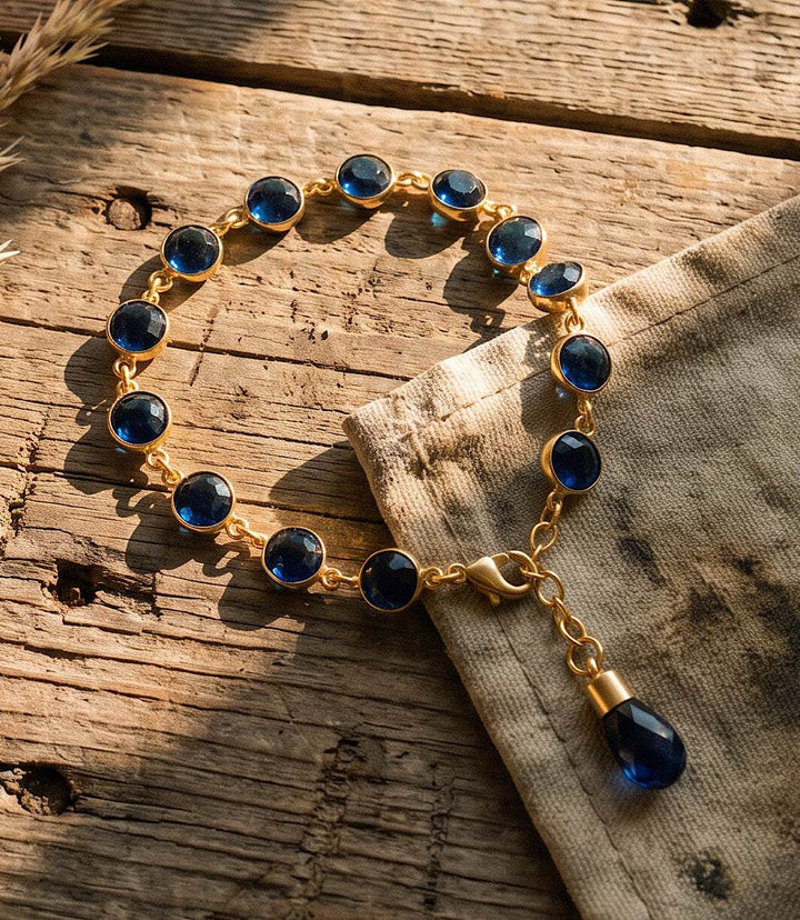 Sapphire crystal bracelet with blue sapphire crystals and gold-tone design on a white background