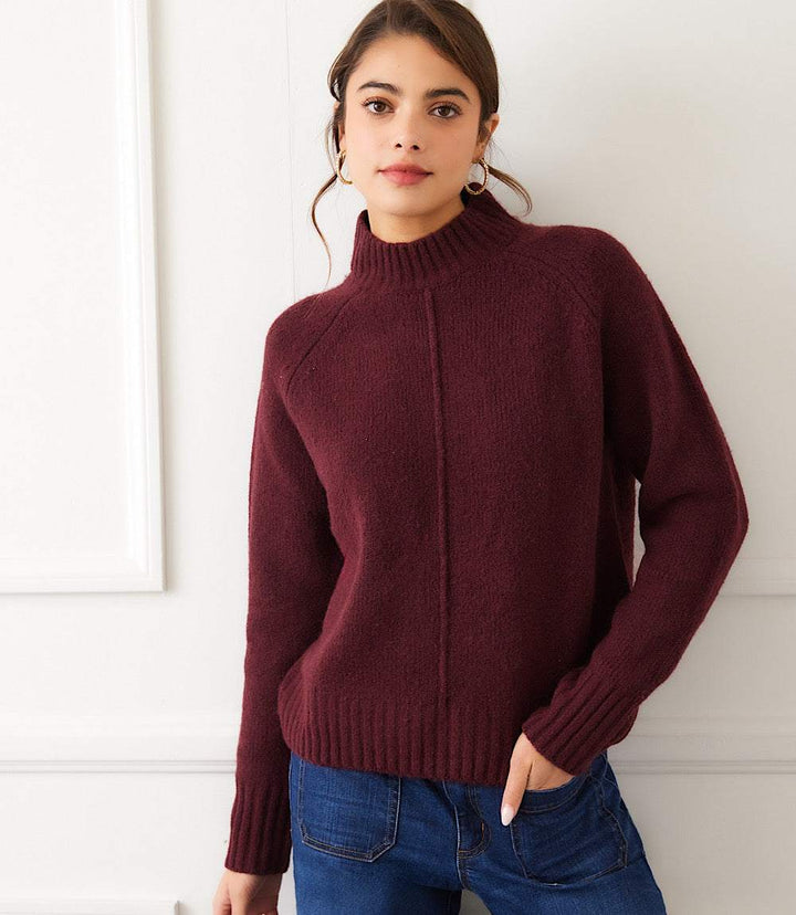 Woman wearing maroon turtleneck sweater with raglan sleeves and exposed center seam