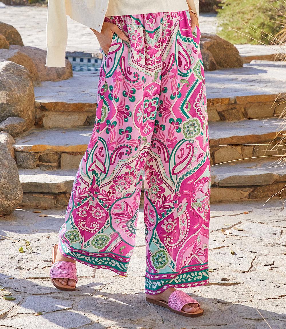 Wide-leg pants with pink orchid background and green Italian tile border print, elastic waistband, and side pockets.