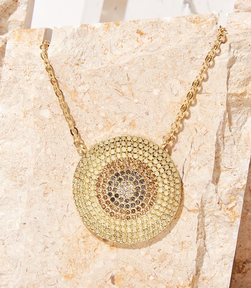 Ombre Pavé Disc Necklace with crystal mosaic design and gold-tone chain on stone background