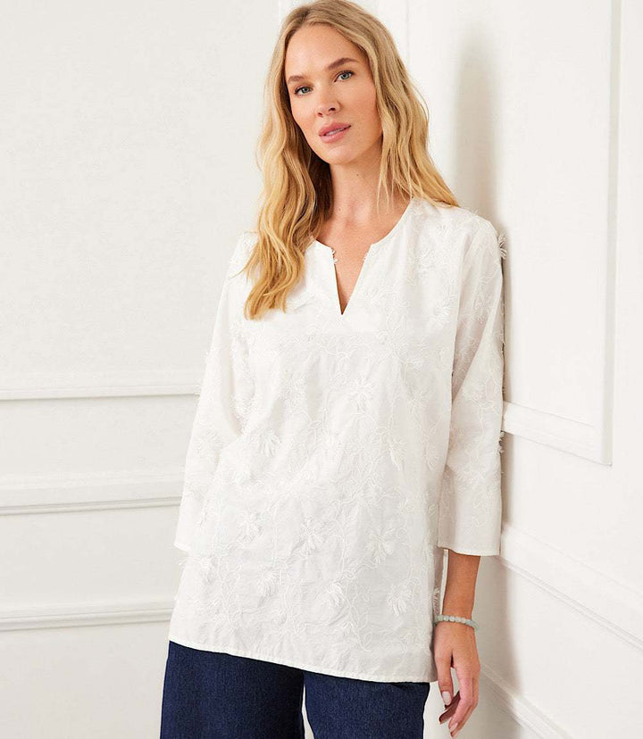 Woman wearing white 3/4 sleeve embroidered tunic with split neck and relaxed fit