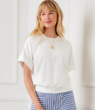 Woman wearing a ribbed cuffed sleeve top with relaxed fit and crew neckline