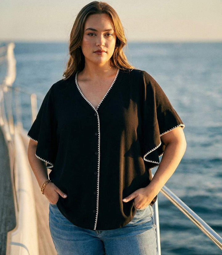 Plus size flutter sleeve top with edge-stitch detailing and shirttail hem in cream color