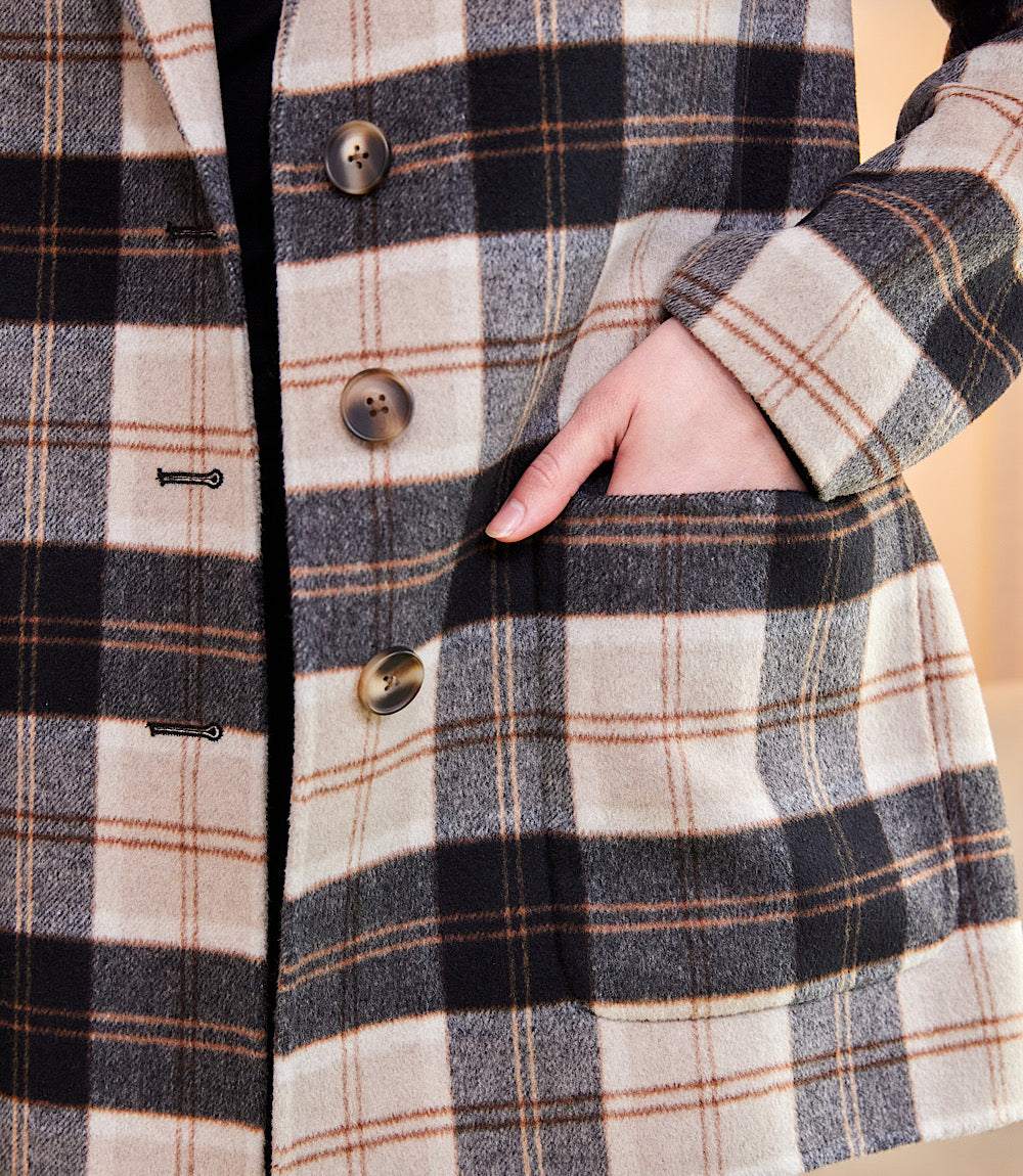 Close-up of oversized brushed plaid blazer with beige, black, and brown pattern showing button closure and front pocket detail