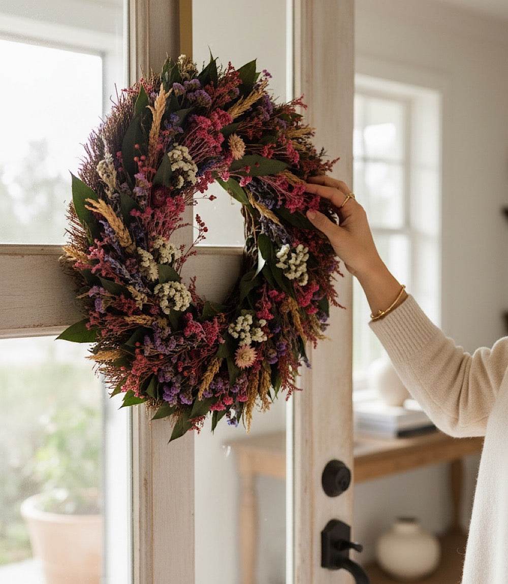 Newport Floral Wreath made of dried flowers and green leaves hanging on a door indoors