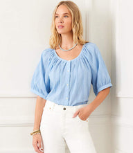 Woman wearing a light blue short sleeve embroidered peasant top with puff sleeves and front buttons