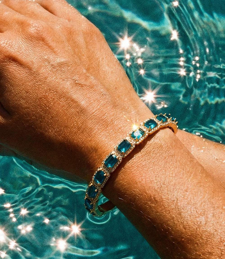 Gemstone cuff bracelet with sapphire blue glass crystals set in 14K gold-plated brass, open design.