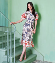 Woman wearing a cotton puff sleeve shirtdress with batik border print and waist belt standing on stairs