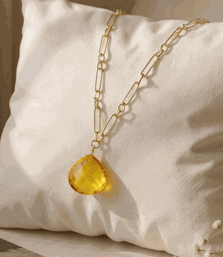 Faceted citrine quartz pendant on gold plated brass chain displayed on white cushion