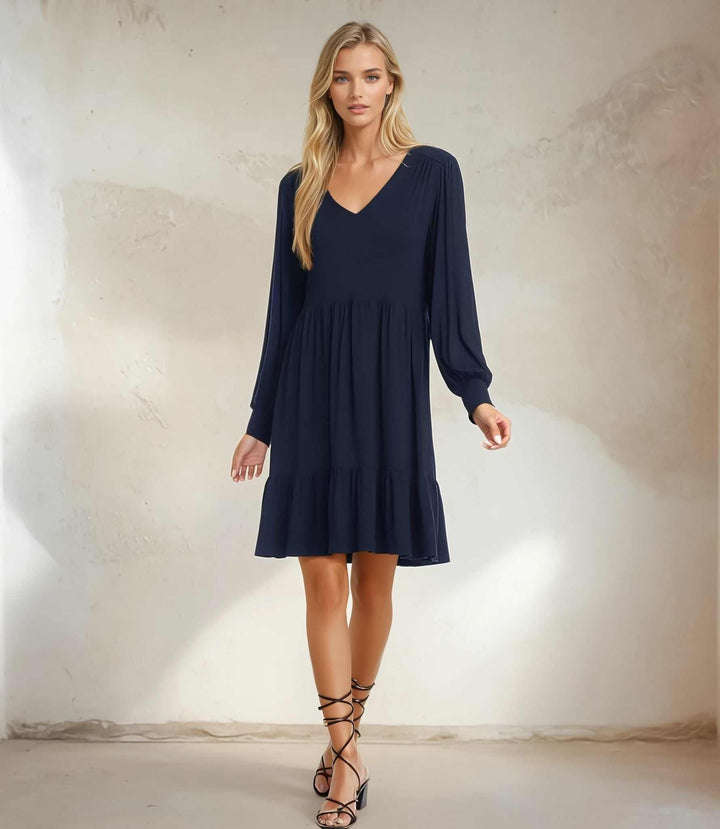 Woman wearing a navy long sleeve tiered dress with V-neckline and gathered cuff sleeves