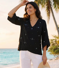 Woman wearing a bracelet sleeve embellished asymmetric top with V-neck and flutter sleeves