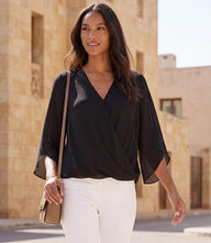 Woman wearing bracelet sleeve drape front crossover top with flare sleeves and V-neck