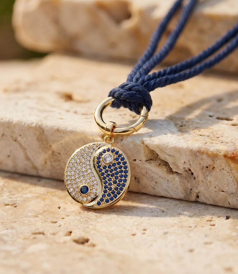 Gold-tone Yin Yang disc necklace with pavé cubic zirconia on navy cotton cord, modern and elegant design