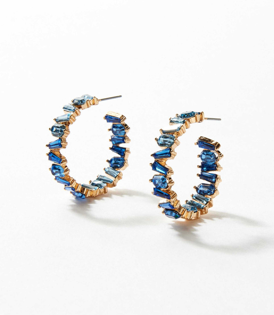 Angled crystal hoop earrings featuring blue crystals set in 14k gold with a 3-inch circumference and 0.25-inch width.
