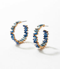 Angled crystal hoop earrings featuring blue crystals set in 14k gold with a 3-inch circumference and 0.25-inch width.