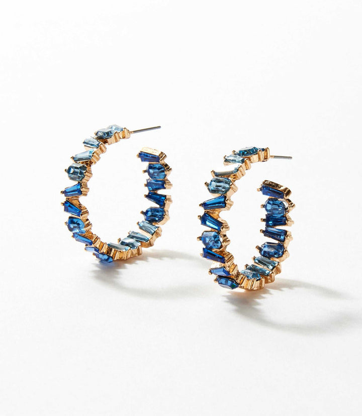 Angled crystal hoop earrings featuring blue crystals set in 14k gold with a 3-inch circumference and 0.25-inch width.