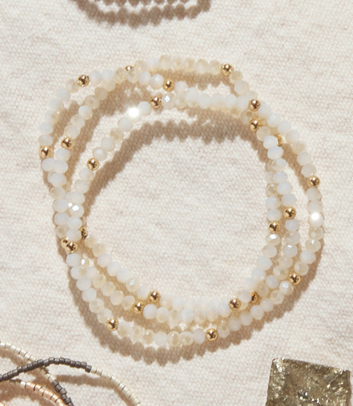 Set of 3 beaded crystal bracelets with white glass beads and gold-filled accents on a light background