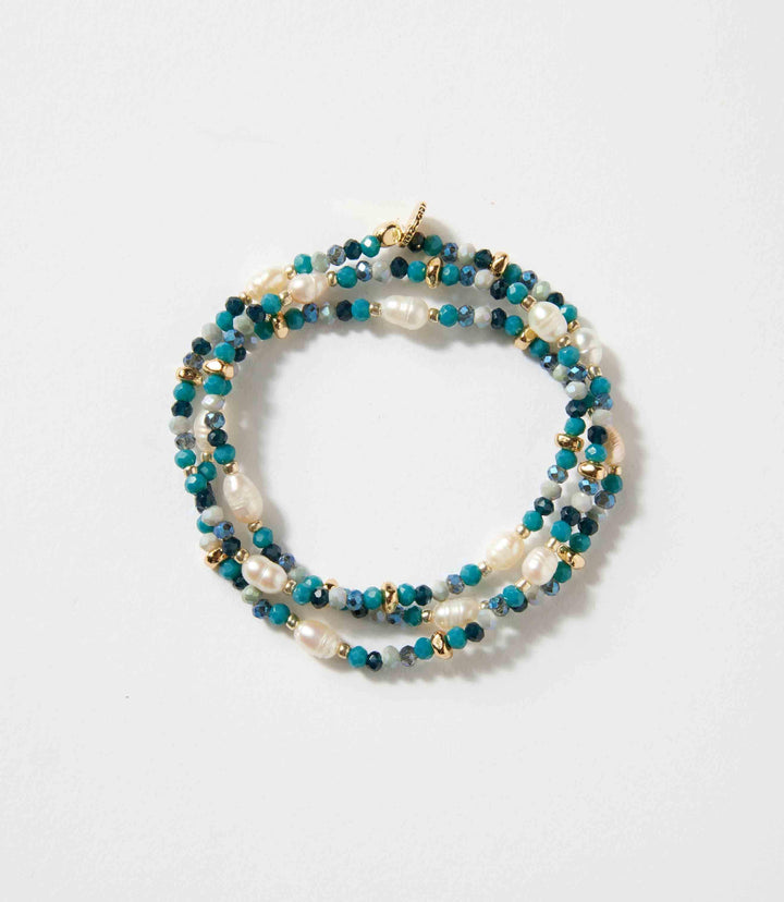 Beaded gemstone and pearl stretch bracelet with mixed blue and gold beads on a white background