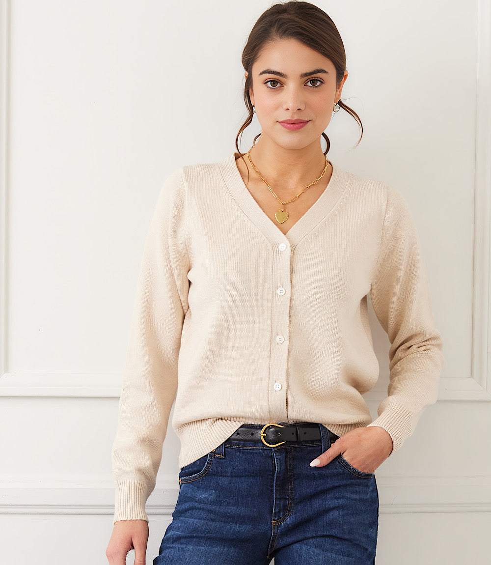 Woman wearing beige V-neck cardigan sweater with tonal buttons and ribbed trims paired with blue jeans