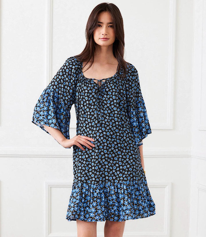Woman wearing a blue pansy print Contrast Ruffle Hem dress with bell sleeves and side pockets