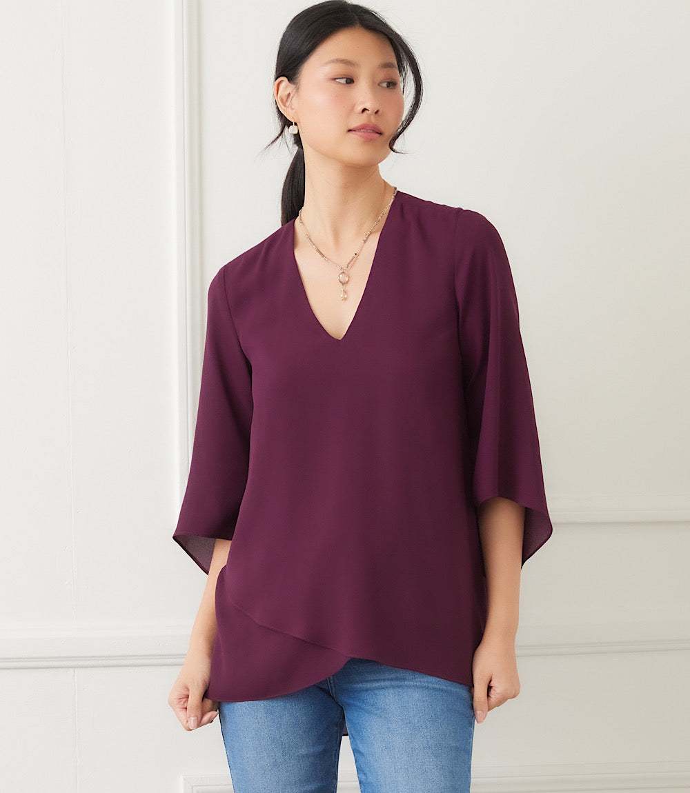 Woman wearing purple silky crepe Bracelet Sleeve Asymmetric Top with V-neck and layered asymmetrical hem.