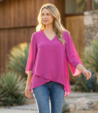 Woman wearing a silky crepe Bracelet Sleeve Asymmetric Top with flare sleeves and layered asymmetrical hem