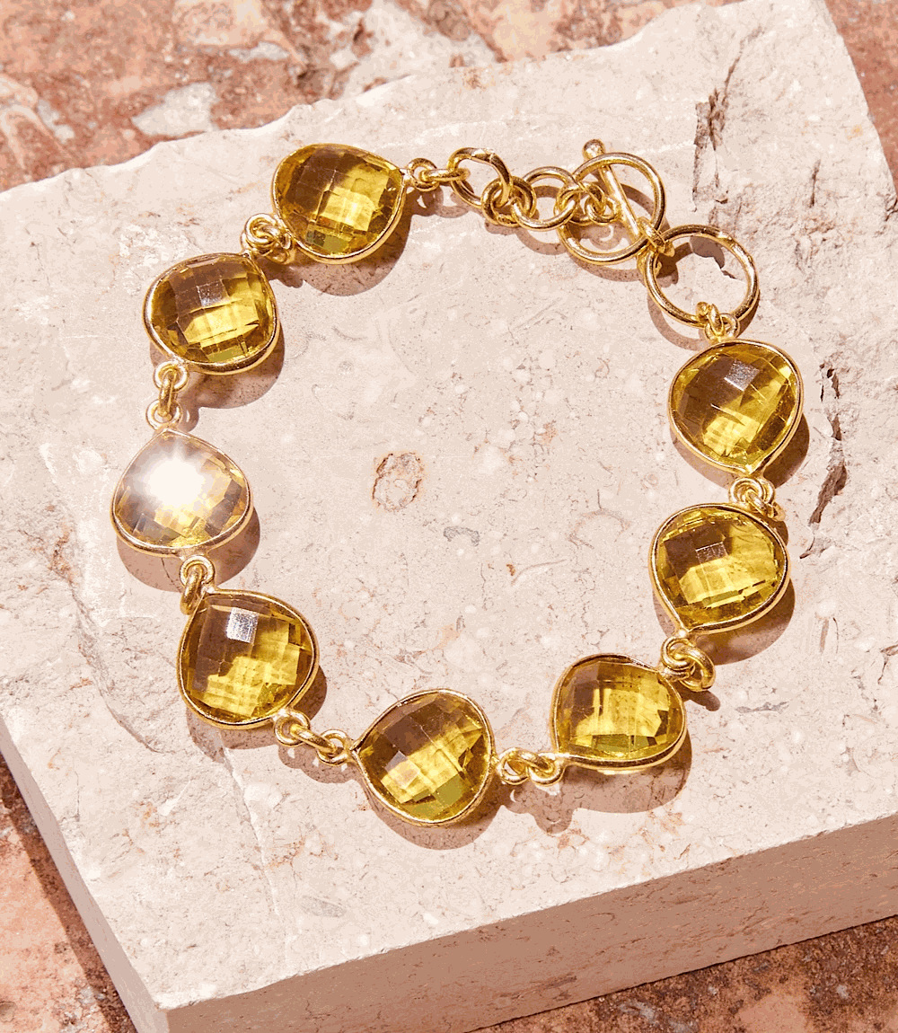 Gold chainlink Citrine Quartz Bracelet with teardrop stones on stone background