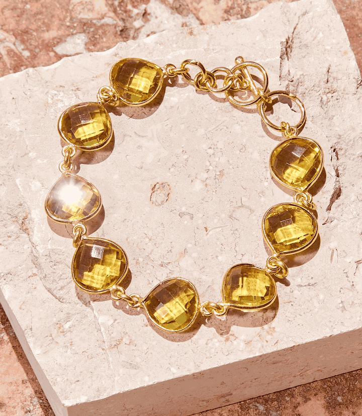 Gold chainlink Citrine Quartz Bracelet with teardrop stones on stone background