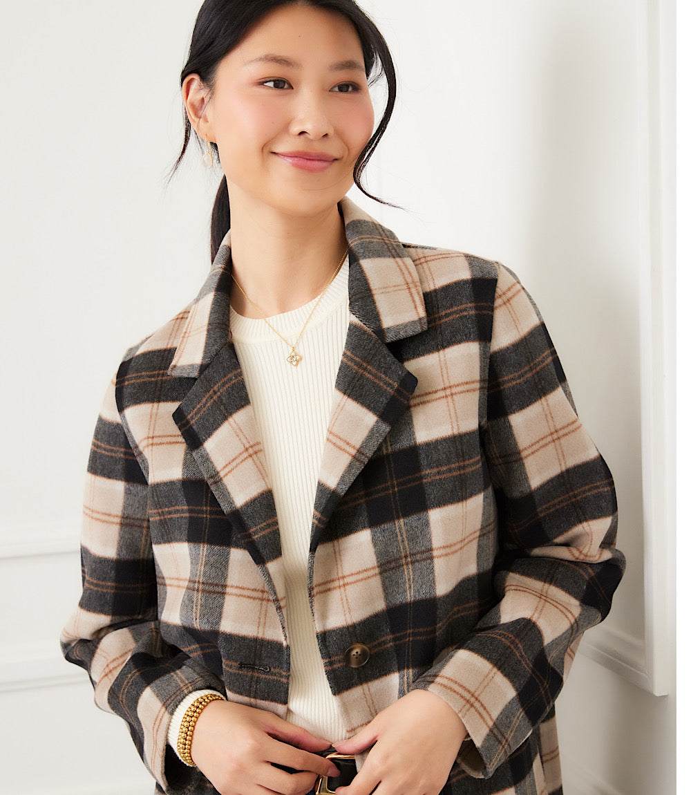 Woman wearing oversized brushed plaid blazer in beige, black, and brown with notched collar and button closure
