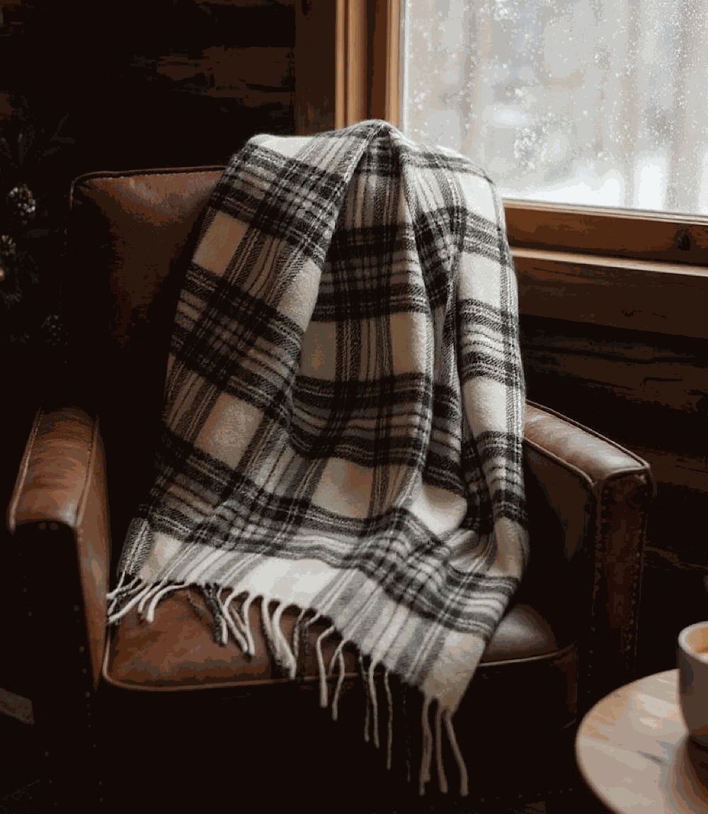 Cozy Merino Wool plaid scarf with fringe draped over leather chair by a window