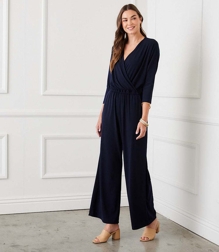 Petite size travel jersey jumpsuit with crossover V-neck, 3/4 sleeves, elastic waistband, side pockets, and wide-leg silhouette in navy blue