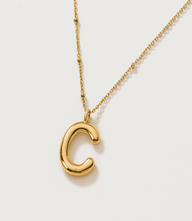 Gold bubble letter charm necklace in 16K gold plated stainless steel with a polished finish