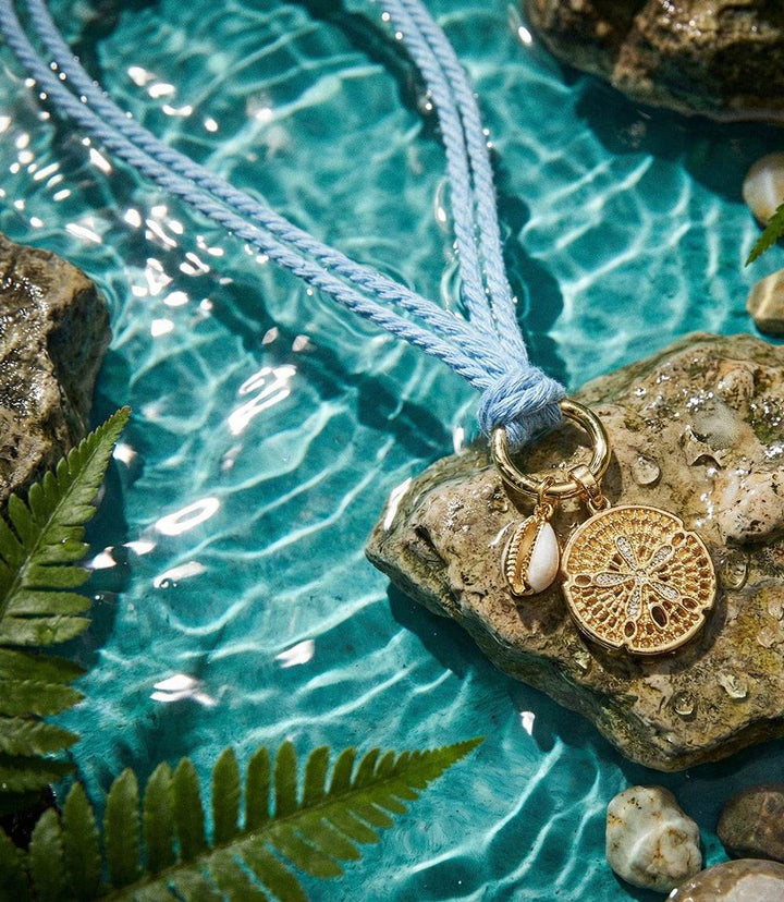Gold-tone sand dollar and cowrie shell necklace with light blue adjustable cotton cord