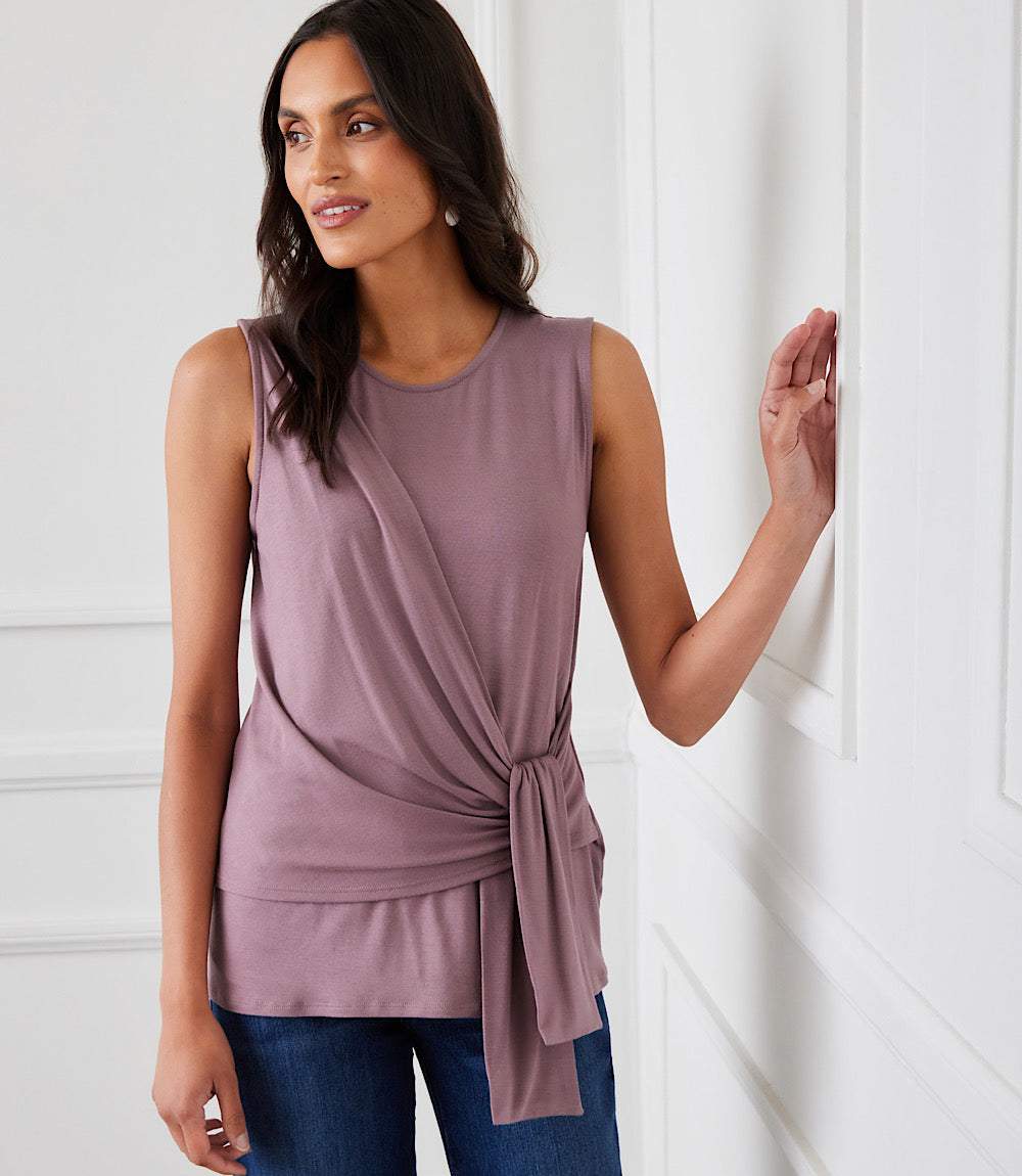 Woman wearing a sleeveless mauve rayon spandex side drape top with a scoop neck and side-tie detail