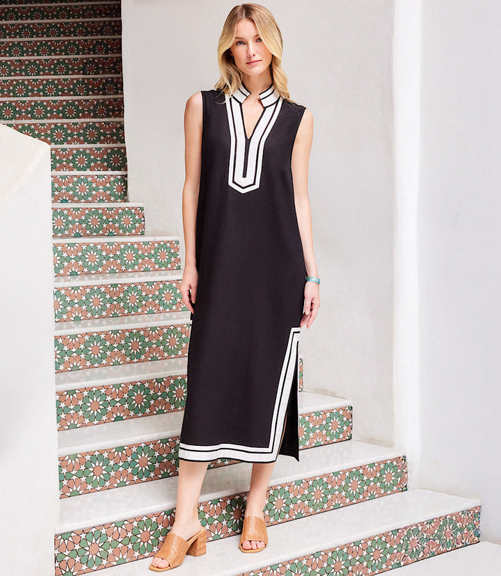 Woman wearing The St. Tropez Sleeveless Midi Dress in black with white trim, featuring a mandarin collar, split neckline, side slits, and midi length.