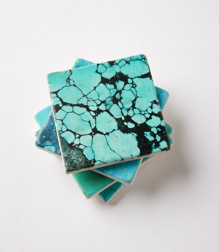 Set of four turquoise marble coasters with unique marbled patterns and cork backing for surface protection
