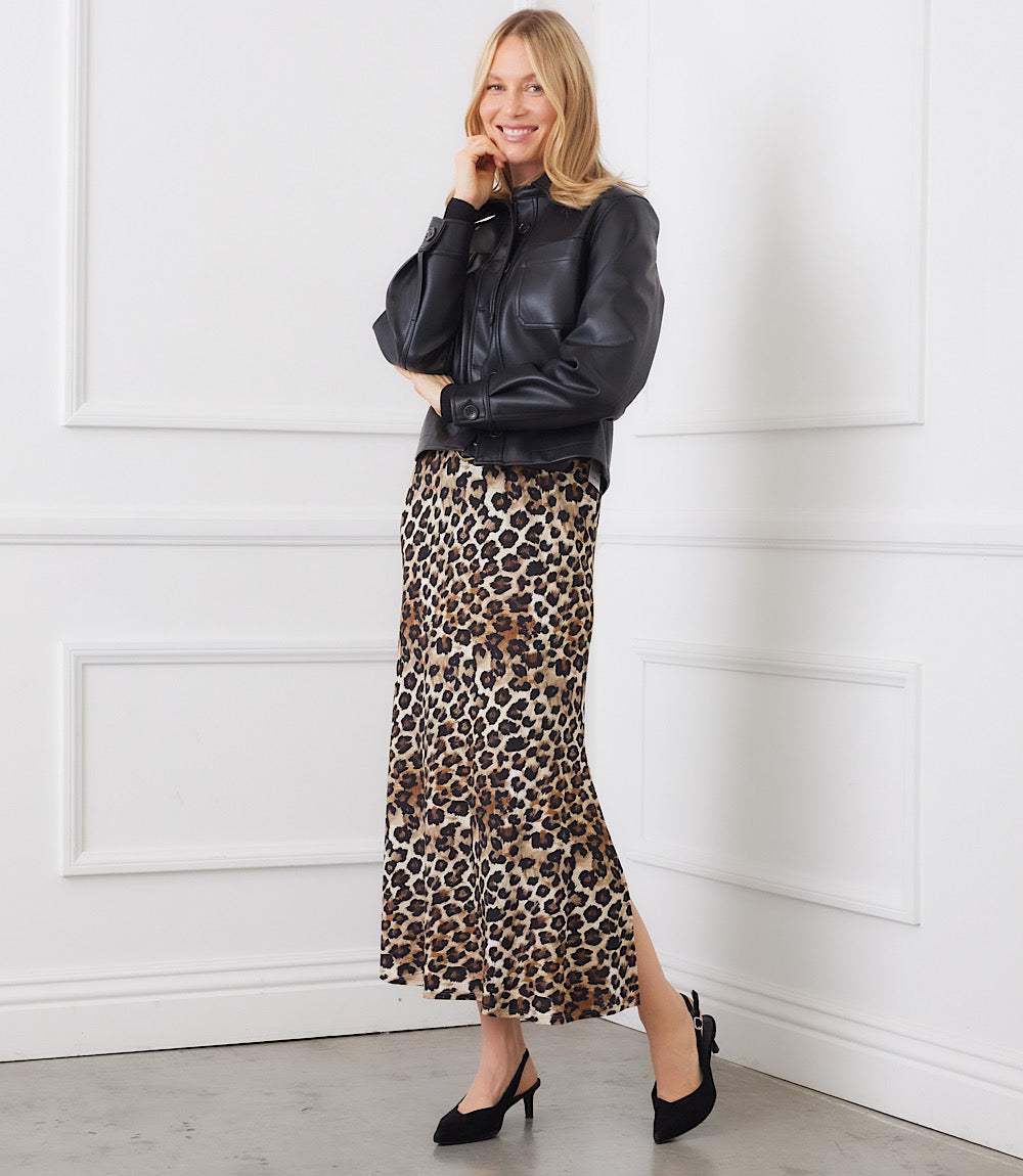 Woman wearing a petite size side-slit midi skirt in leopard print paired with a black leather jacket and black heels
