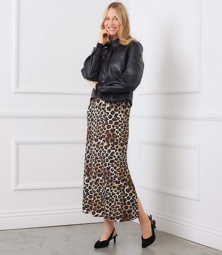 Woman wearing a petite size side-slit midi skirt in leopard print paired with a black leather jacket and black heels