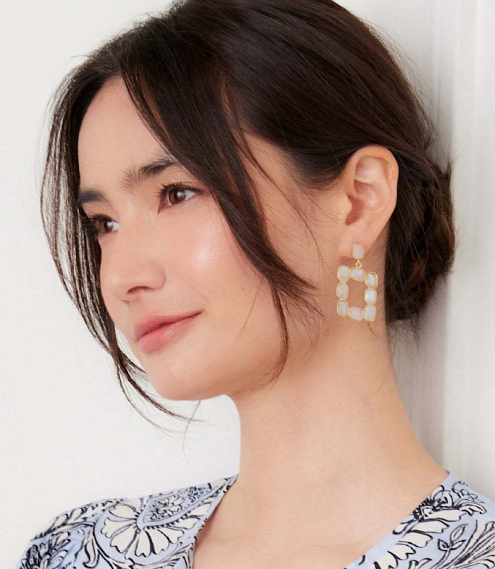 Close-up of a woman wearing rectangular gemstone bezel earrings with moonstone set in 18K gold plated sterling silver frames