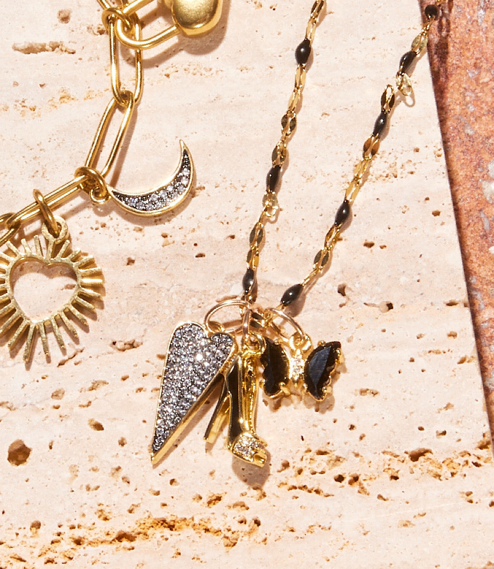 Uptown Girl Charm necklace with gold-toned chain, pavé heart, high heel, and butterfly charms featuring cubic zirconia and black enamel accents