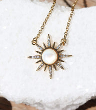 Moonstone cabochon necklace with gold sunburst pendant on gold-toned chain